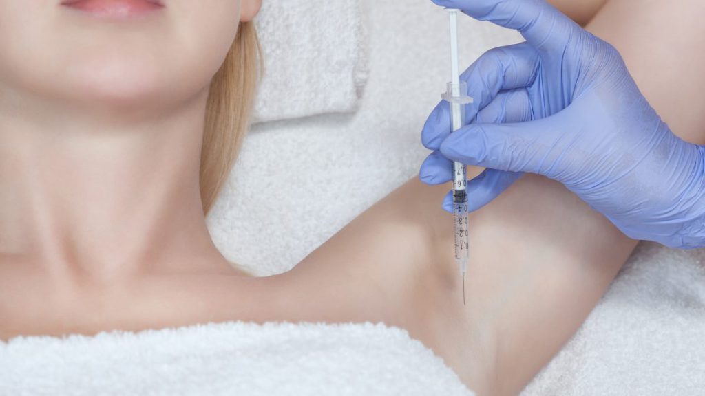 mulher injetando substancia nas axilas de outra mulher